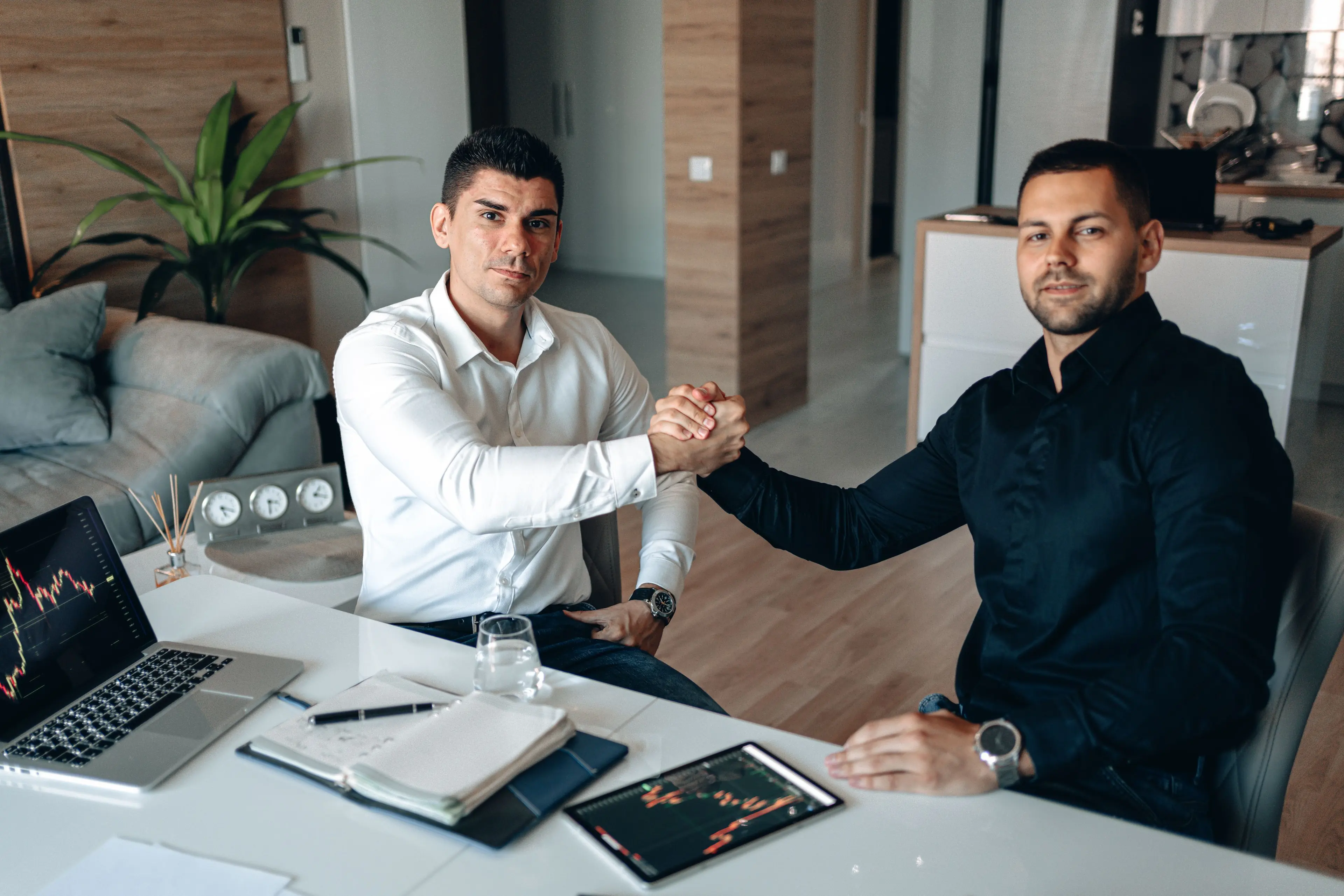 Two business partners clasping hands across their desk — therapy for business partners in Los Angeles