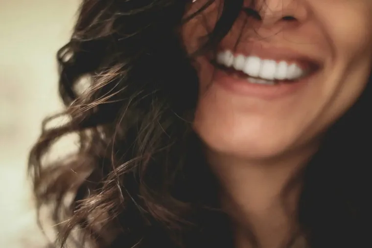 A woman laughing warmly, hair across her face — Emotionally Focused Therapy (EFT) for couples in Los Angeles