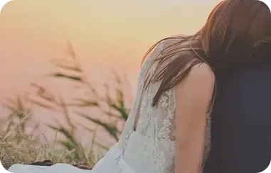 A bride in lace resting her head on her partner’s shoulder at sunset — premarital therapy in Los Angeles