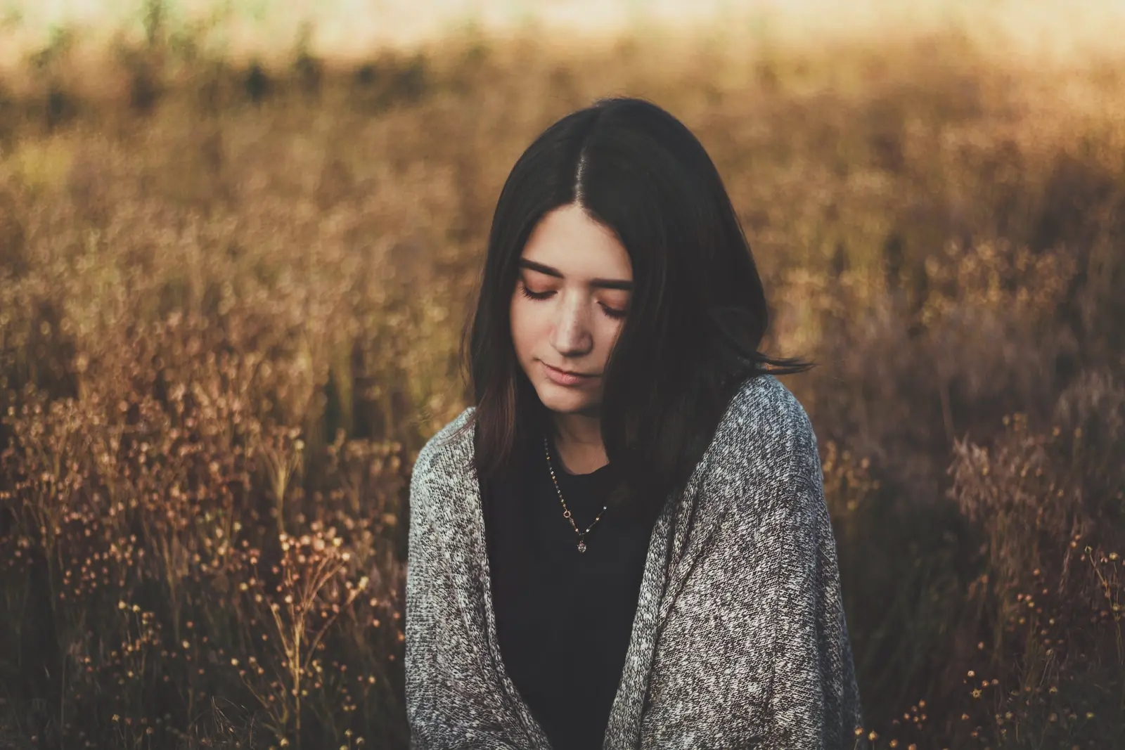 A woman with her eyes closed, calm and reflective in a sunlit golden field — depression therapy in Los Angeles