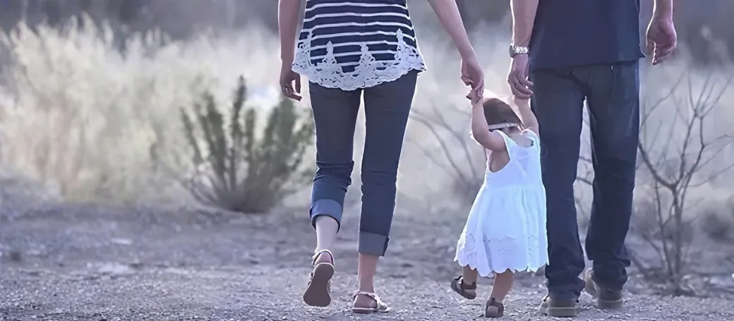 Two parents walking a dirt path with their toddler between them — family therapy in Los Angeles