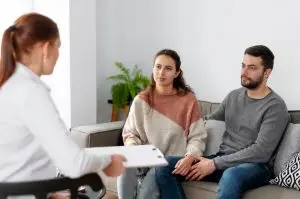 A couple sitting on a couch during a therapy session with a therapist in Los Angeles, discussing their relationship concerns.
