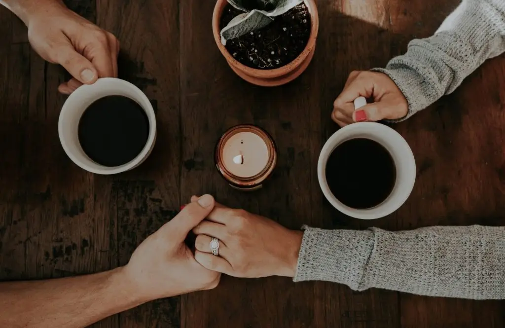 Two people holding white ceramic mugs, engaging in calm conversation, reflecting healthy communication and connection. And healthy anger in relationships.