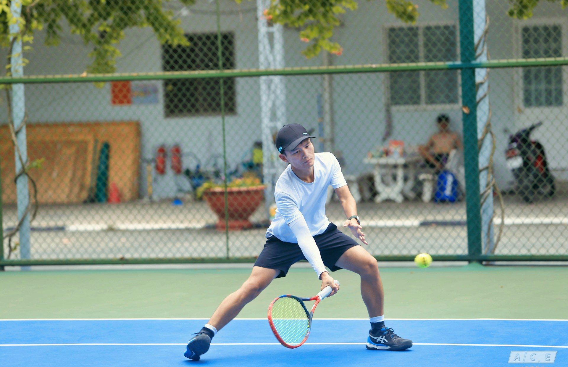 An adult on a tennis court holding a racquet, embodying the importance of play for adult mental health