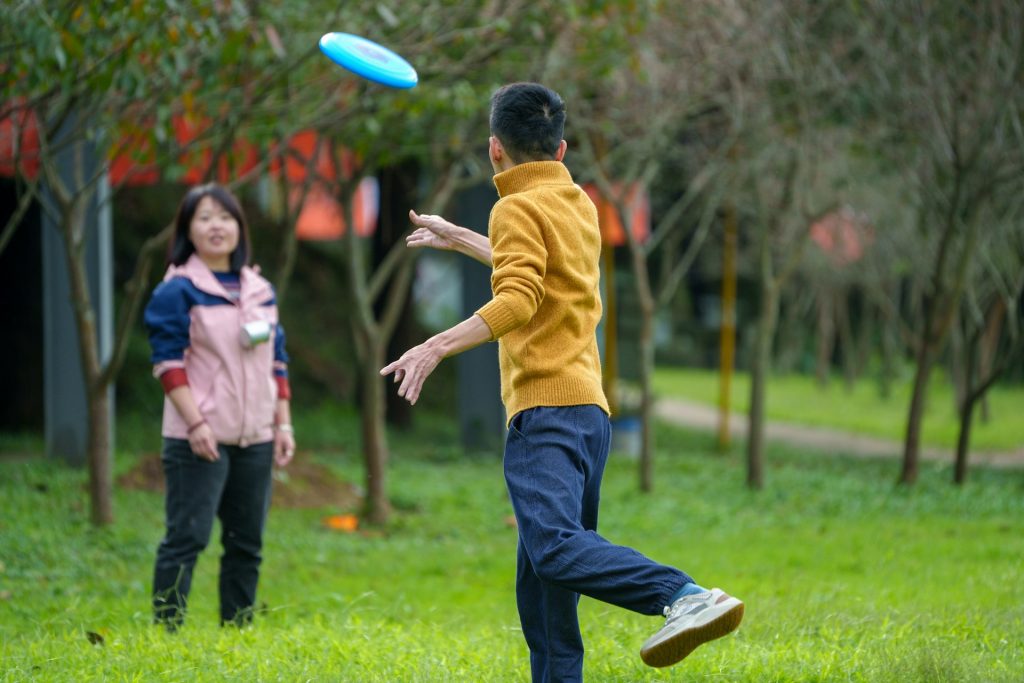 Two adults playing frisbee in a park, showing the importance of play in adult mental health.