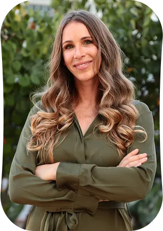 Smiling female therapist with arms crossed outdoors."