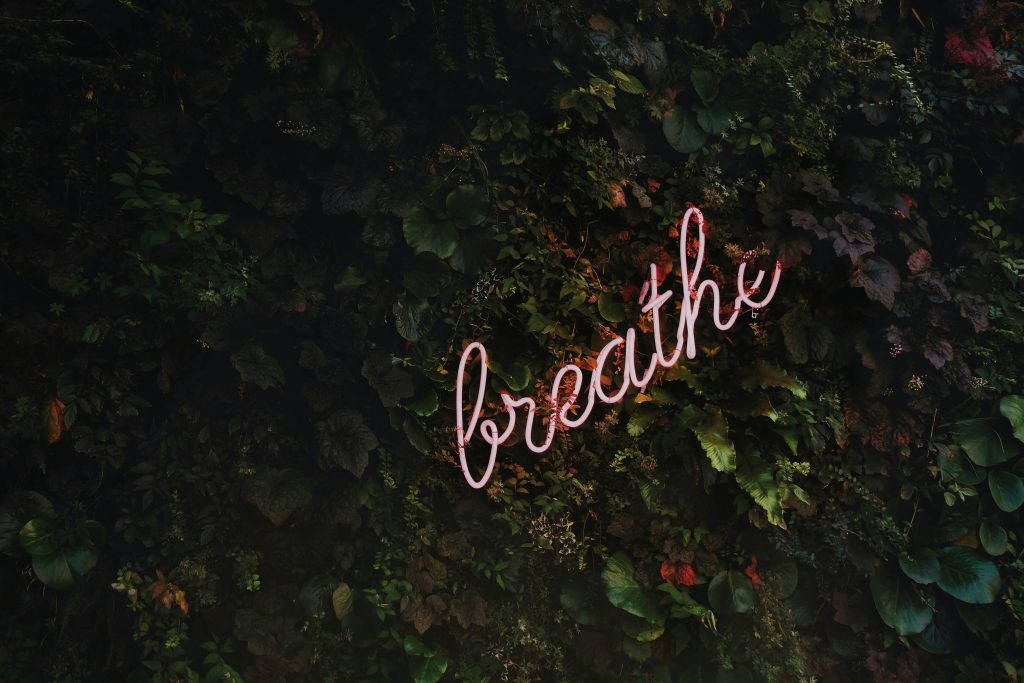 Neon sign displaying the word “breathe” as a visual cue for mindful breathing techniques for stress relief