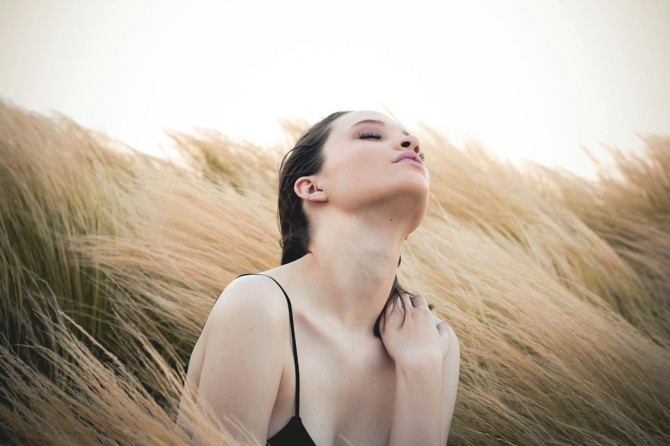 Woman sitting cross-legged in nature, practicing mindful breathing techniques for stress relief