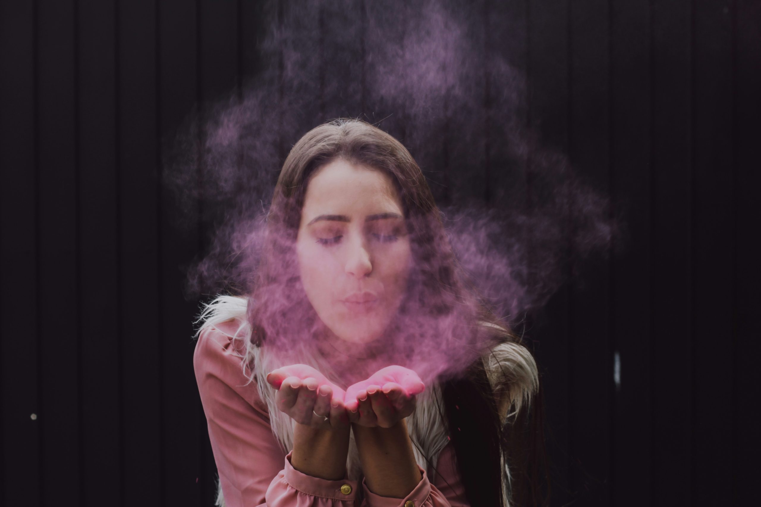 Woman exhaling into her hands, symbolizing mindful breathing techniques for stress relief